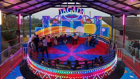 Tagada ride where people are sitting on chairs and holding onto the the railing Tagada has so that they don't fall when it starts rotating.