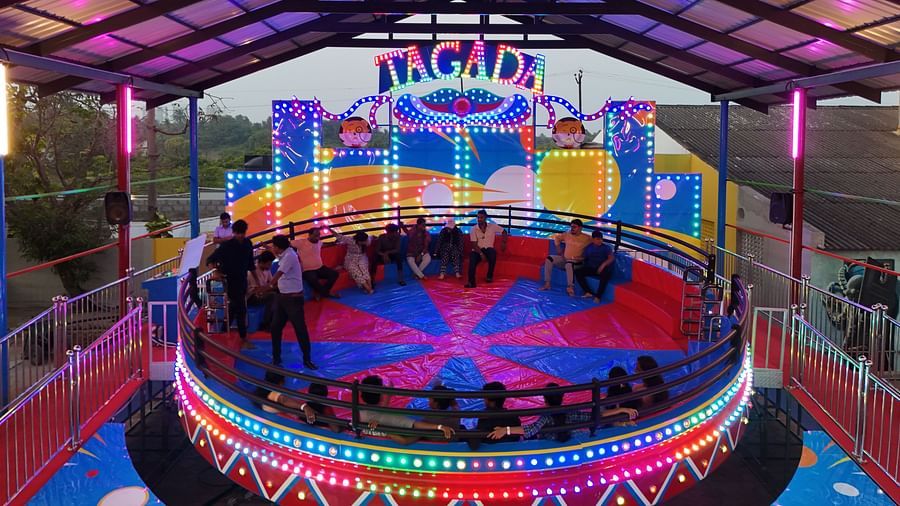 Tagada ride where people are sitting on chairs and holding onto the the railing Tagada has so that they don't fall when it starts rotating.