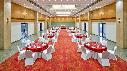 Image of a banquet hall in Bhopal with round tables and chairs arranged around it at Tulip Inn, Bhopal.