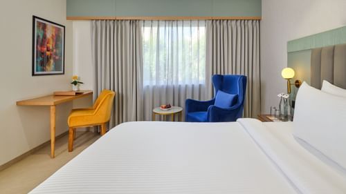 A side view of a room in Bhopal featuring a bed and a seating area situated to the side at  Tulip Inn, Bhopal.