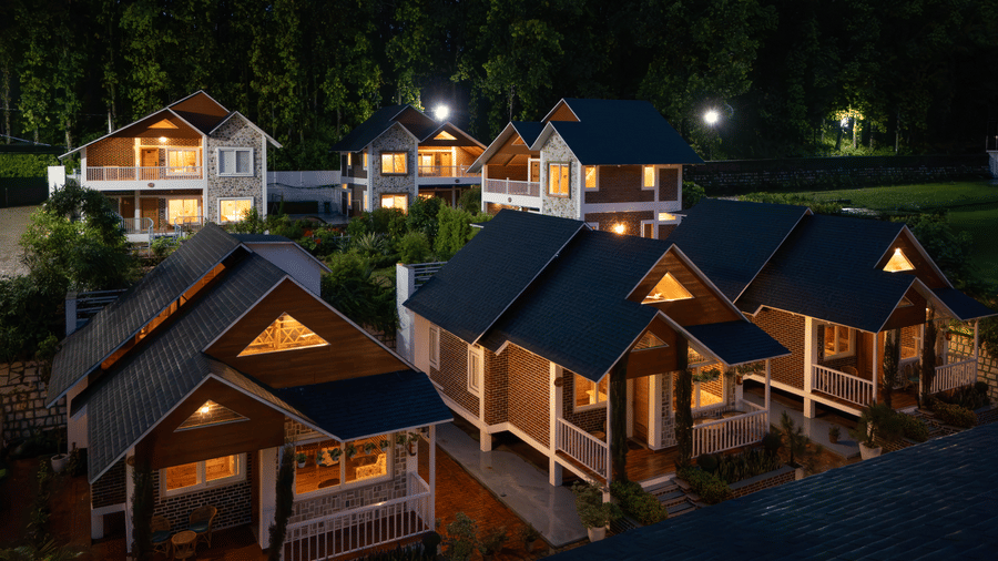A row of wooden cottages lit up at night, surrounded by trees - Megha Resort & Villas, Dehradun