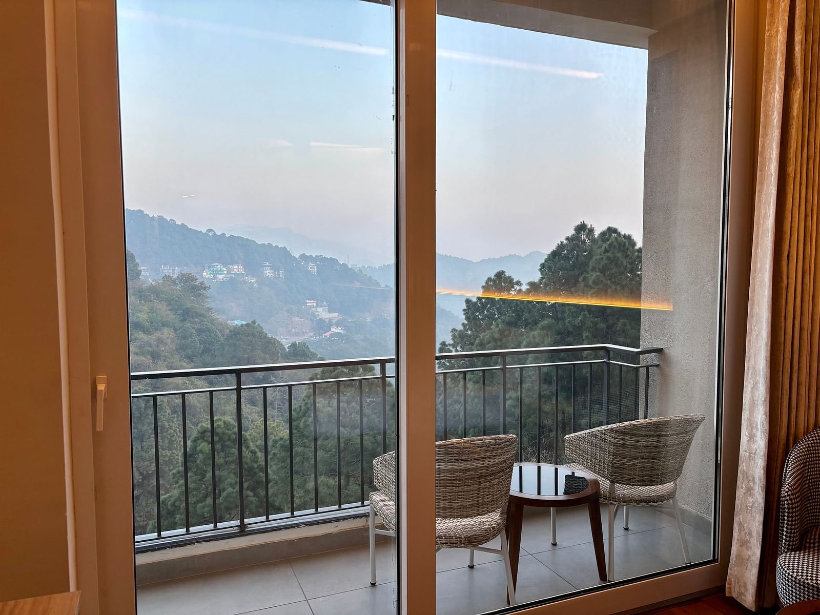 Balcony view with chairs and a table overlooking scenic hills and greenery at ARNISA Boutique Hotel