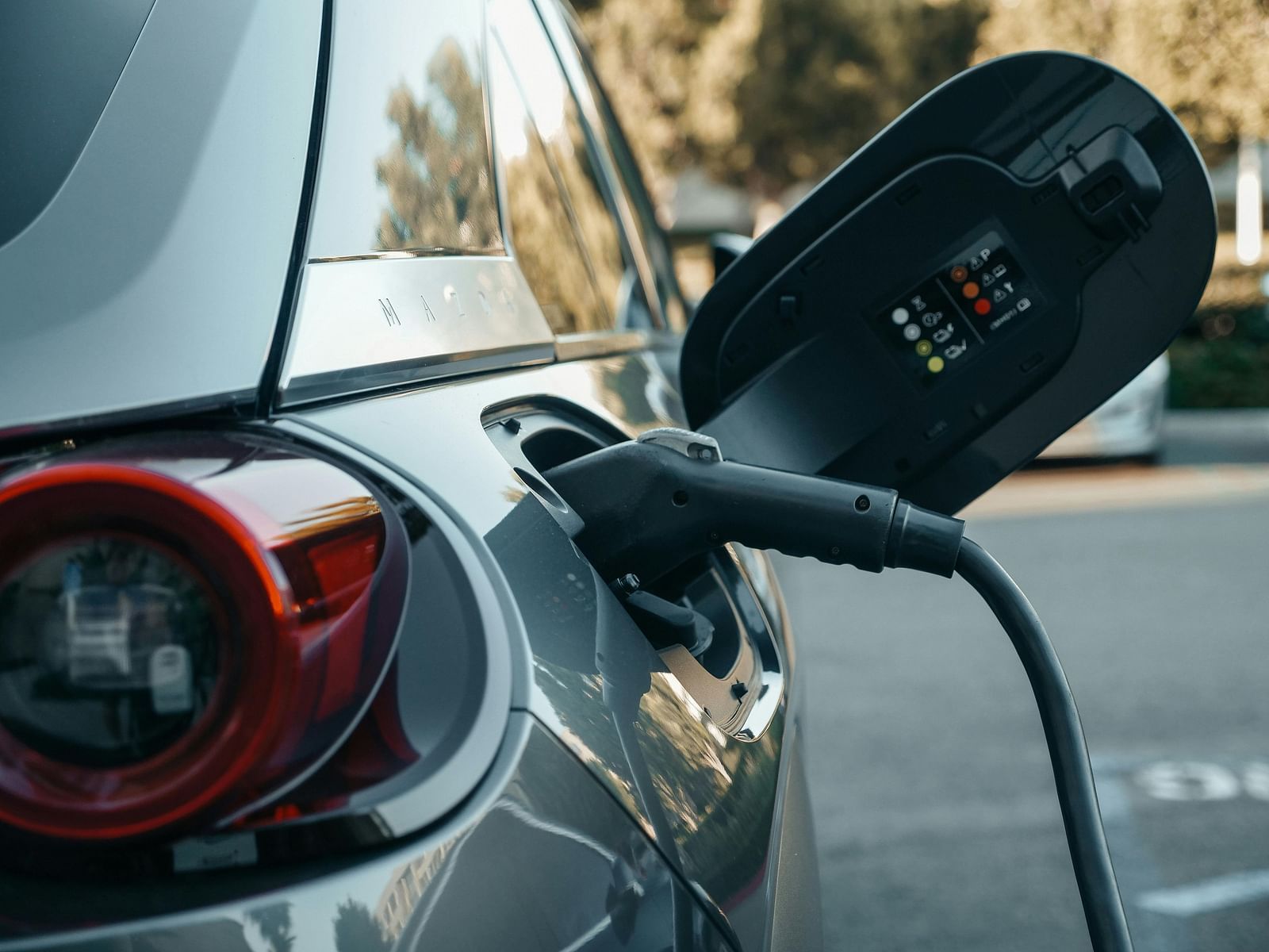 An electric car plugged in and charging at a charging station.