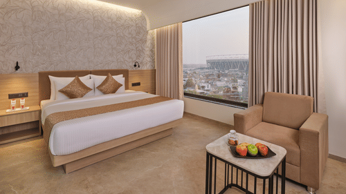 Luxurious hotel room with king bed, city view, and warm, inviting decor at Biznotel by Pride Motera, Ahmedabad