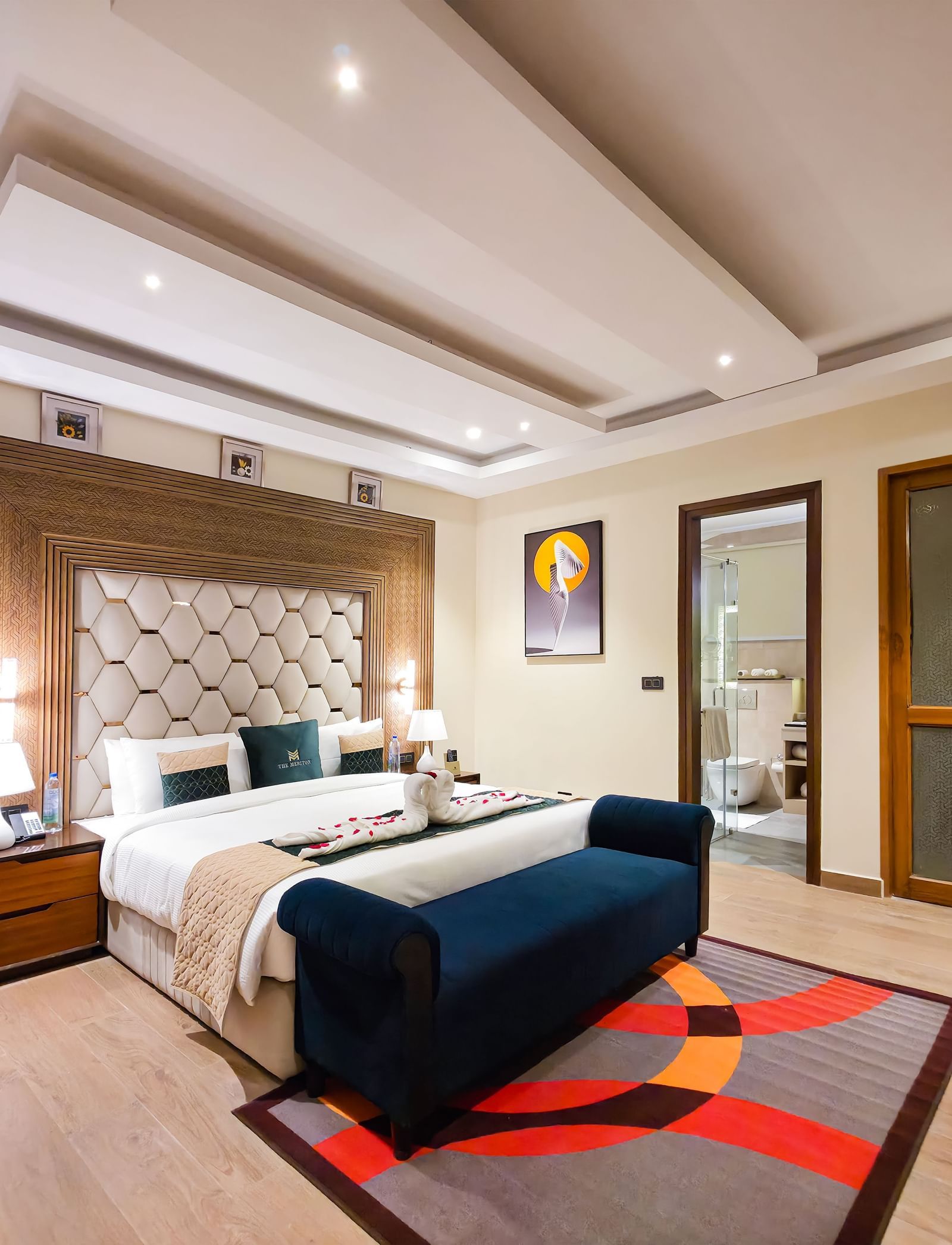 A wide angle shot of the bedroom at the Empress Suite featuring a plush double bed along with a rug on the floor in front of it at The Meriton.