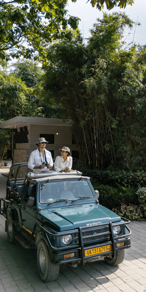 An open vehicle driving along a paved path with people seated inside and greenery on both sides.