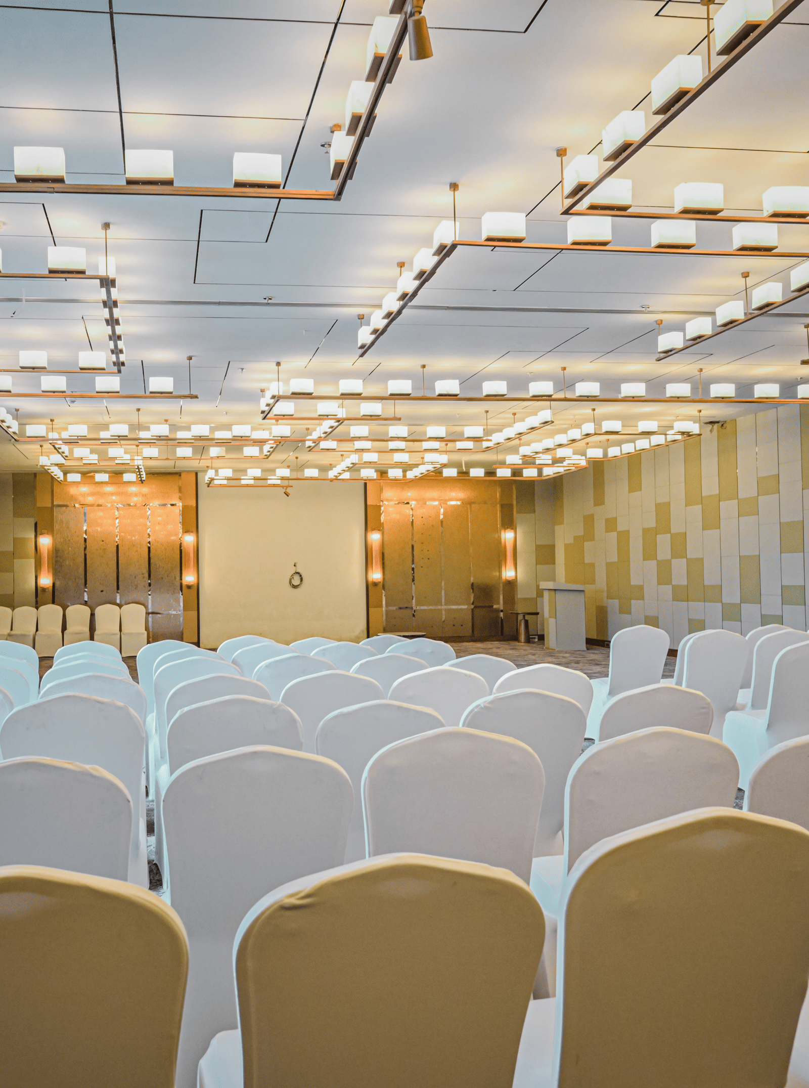 A close-up view of the front rows of chairs in an event space, with a stage and backdrop visible in the distance.