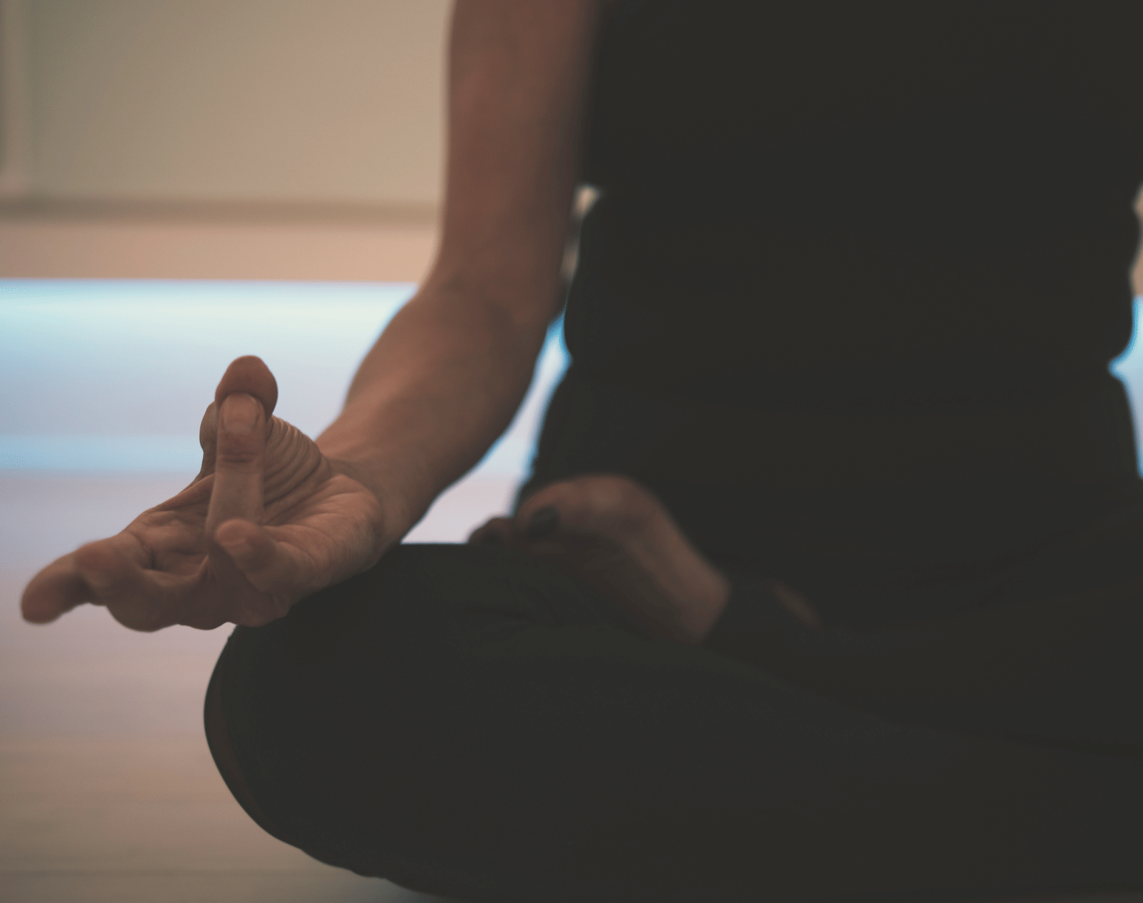 Close-up of a woman sitting in a cross-legged yoga pose indoors.