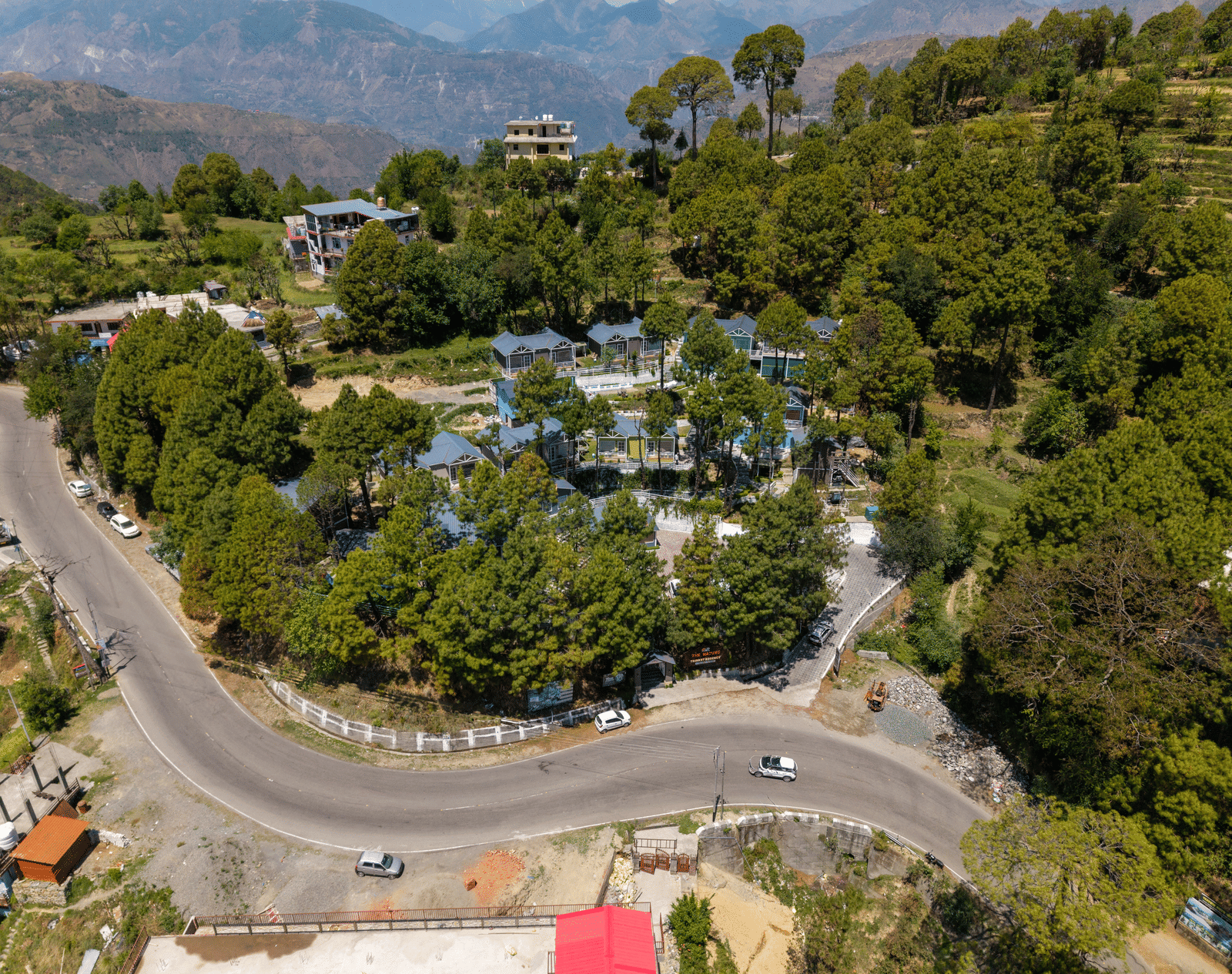 An elevated shot shows a winding road through a hilly landscape with trees and buildings - DLS Nature Trinket Resort, Dalhousie