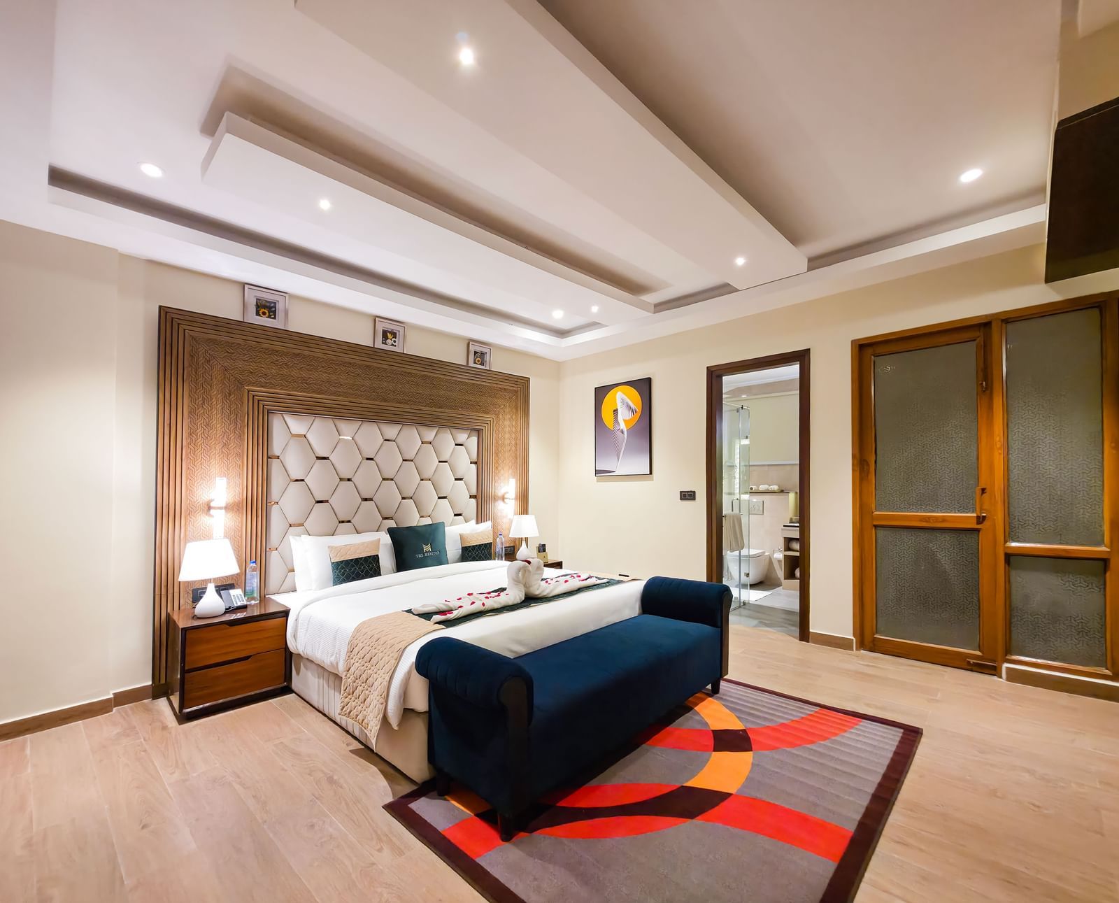 A wide angle shot of the bedroom at the Empress Suite featuring a plush double bed along with a rug on the floor in front of it at The Meriton.