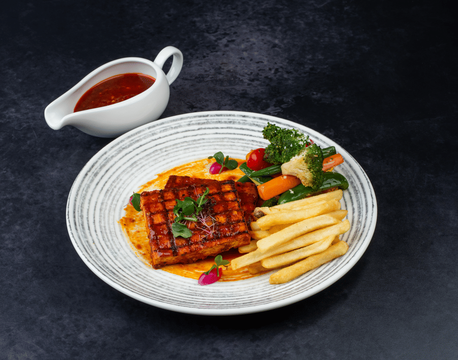 Tofu Seoul Steak served with some vegetables, french fries, and a sauce at The Wild Fork restaurant in La Marvella, Bengaluru.