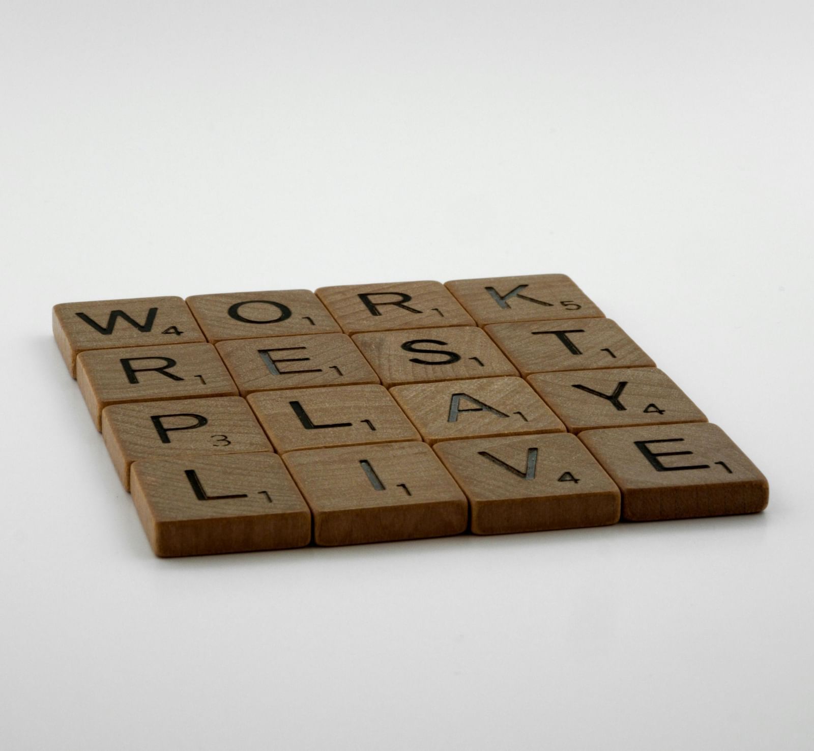 A Scrabble tile arrangement spelling out 'WORK', 'REST', 'PLAY', and 'LIVE'.