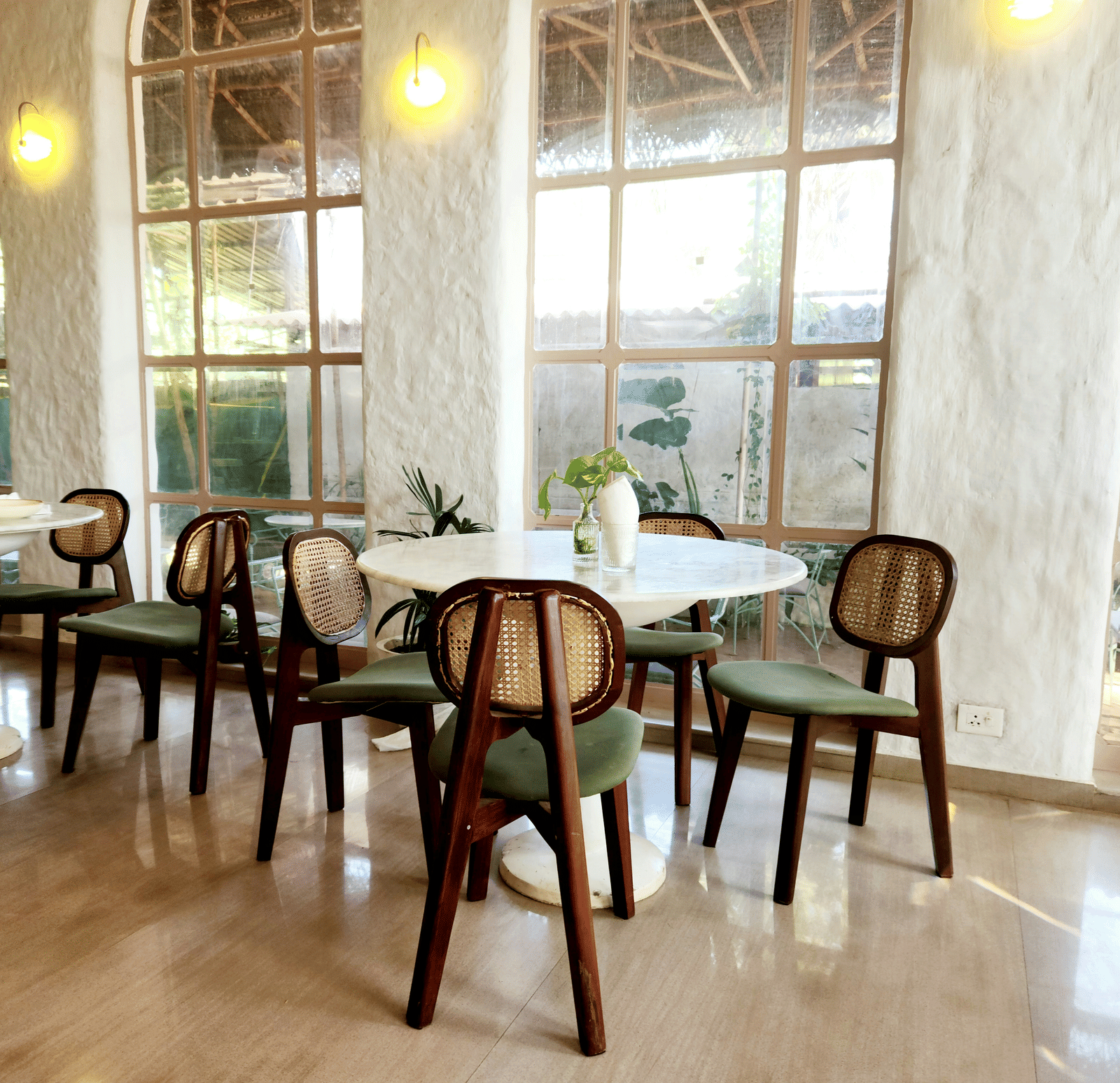 An empty indoor dining room with several tables and chairs near large windows.