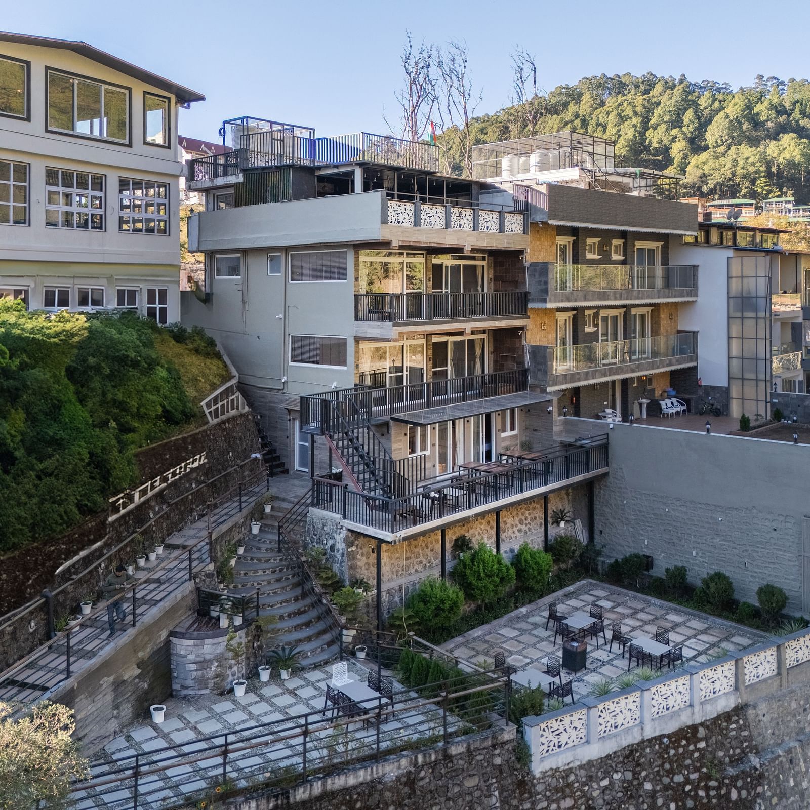 Exterior view of the hotel building with surrounding greenery and hillside landscape in the background.