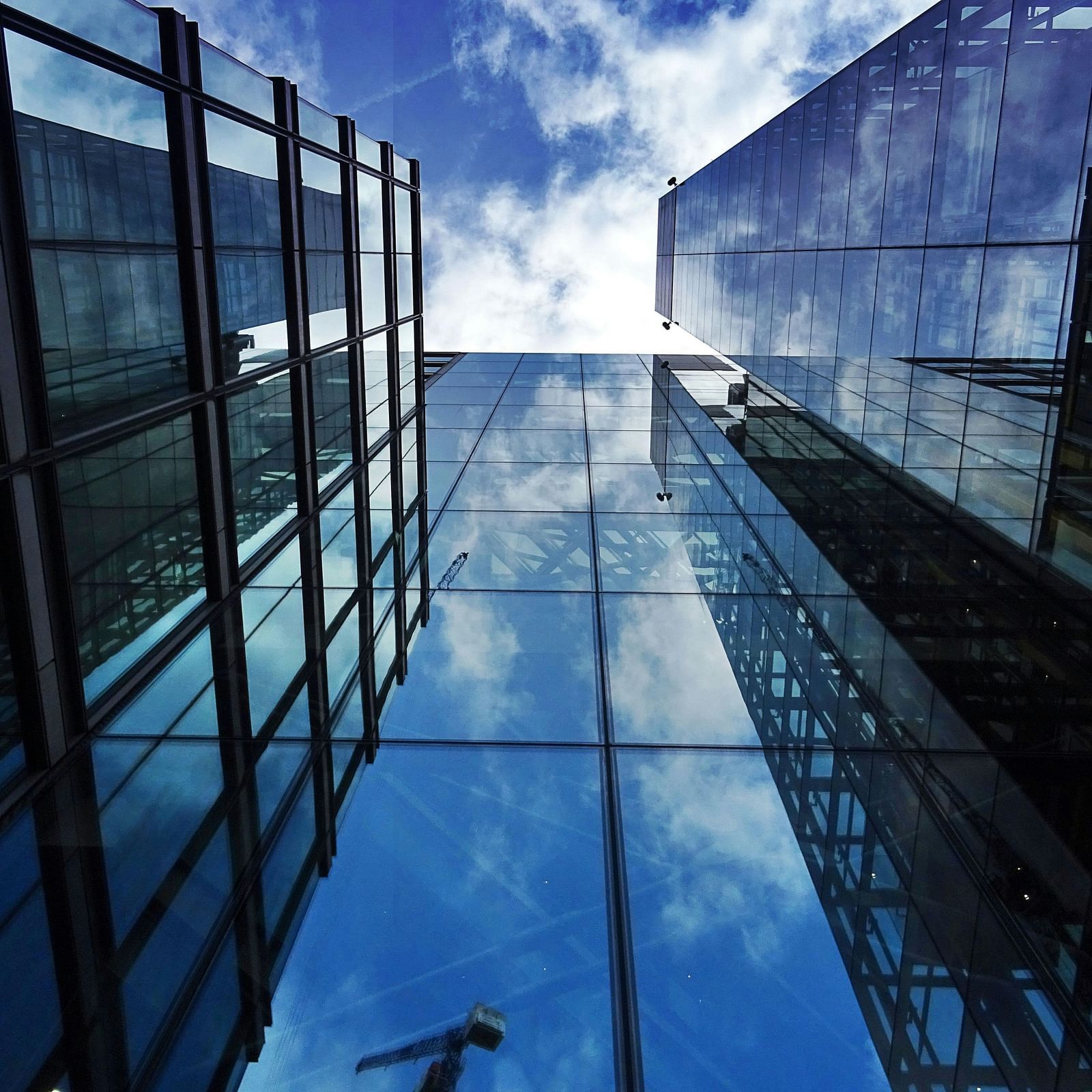 A worm's eye view of a glass building during a sunny day.