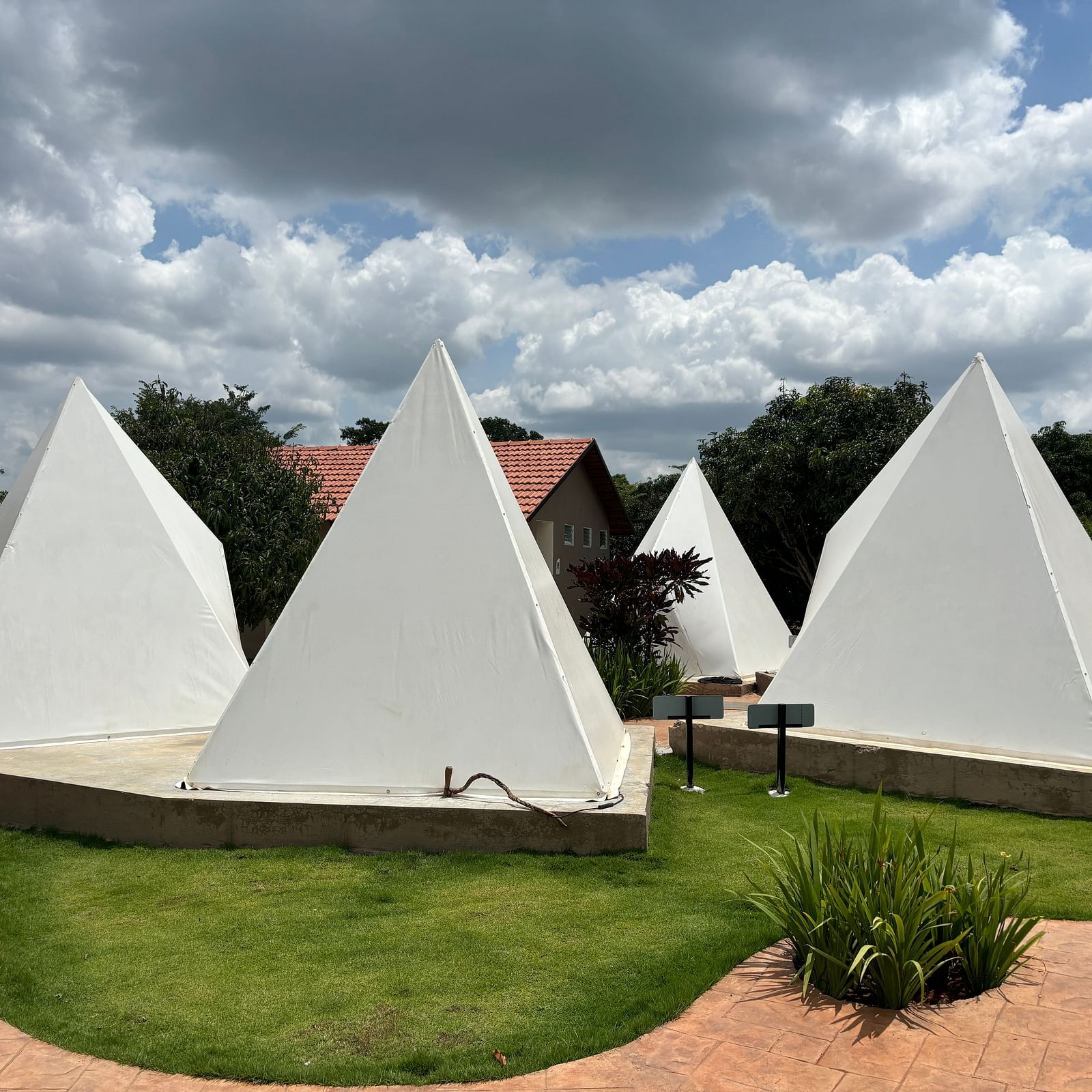 A scenic view of a resort area with tents lined along a neat walkway, surrounded by a well-maintained lawn.