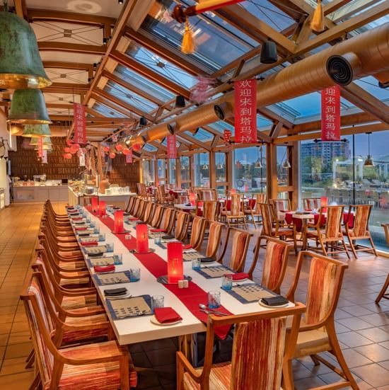 Elegant dining area with a long banquet-style table, wooden chairs, and warm lighting at O by Tamara, Trivandrum.