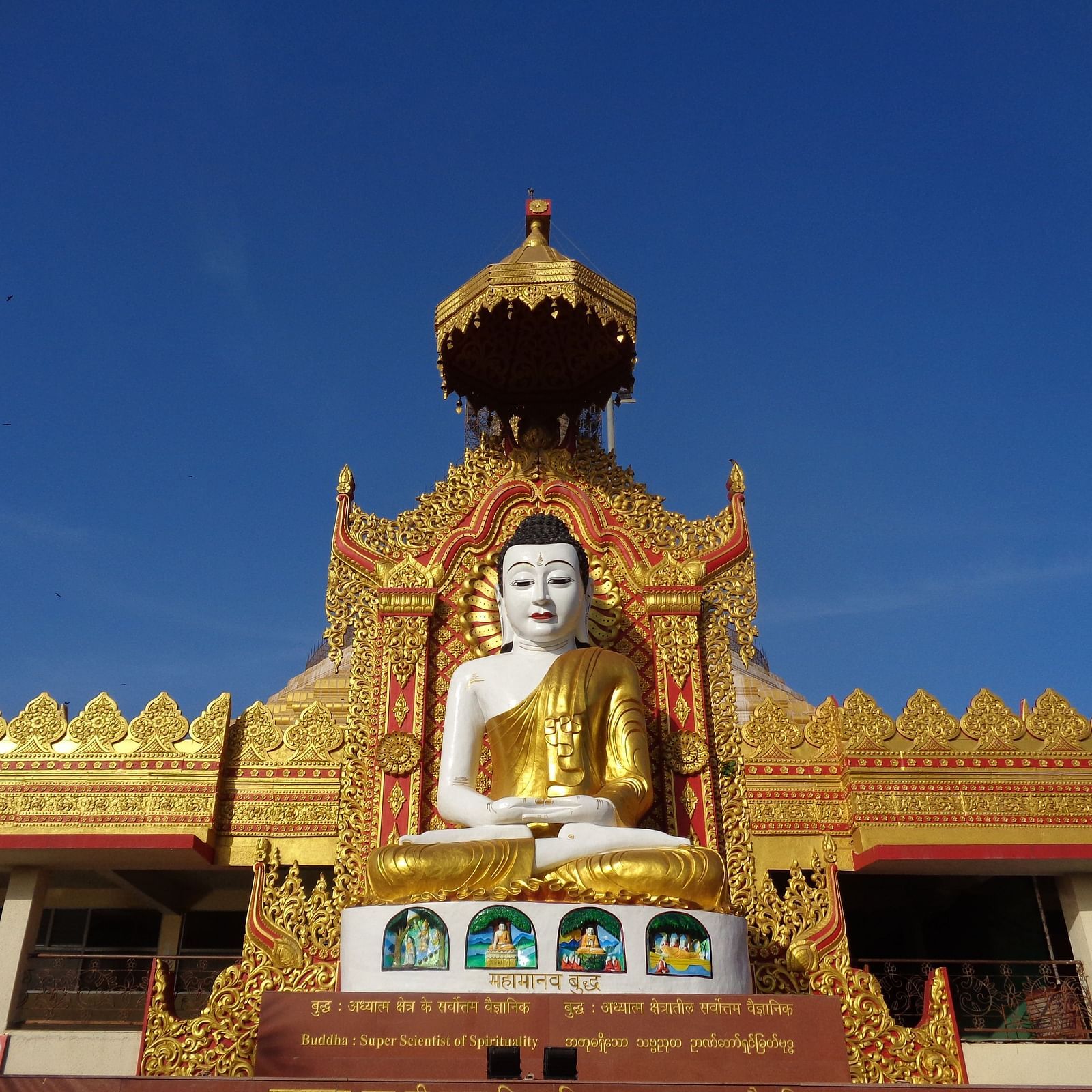 Statue of Lord Buddha in front of a temple on a clear blue day