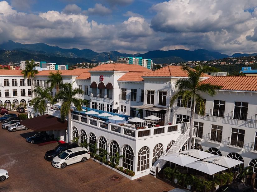 An aerial image of our hotel in Kingston, embraced by lush green palm trees and a spacious parking area - S Hotel Kingston, Jamaica