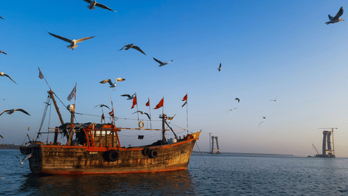 A solitary fishing boat in the ocean near Dwarka with birds flying above the boat