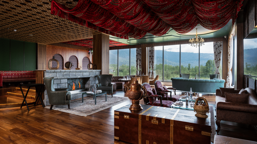Stylish lounge area at Mountnoor Sarovar Premiere, Pahalgam featuring warm interiors and panoramic valley views.