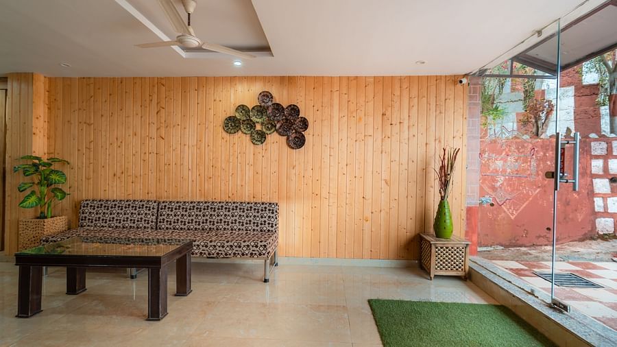 Sitting area at the reception of Flutter Hotels and Resorts, Lansdowne with a sofa, table, wooden decors, carpet and flower vase.