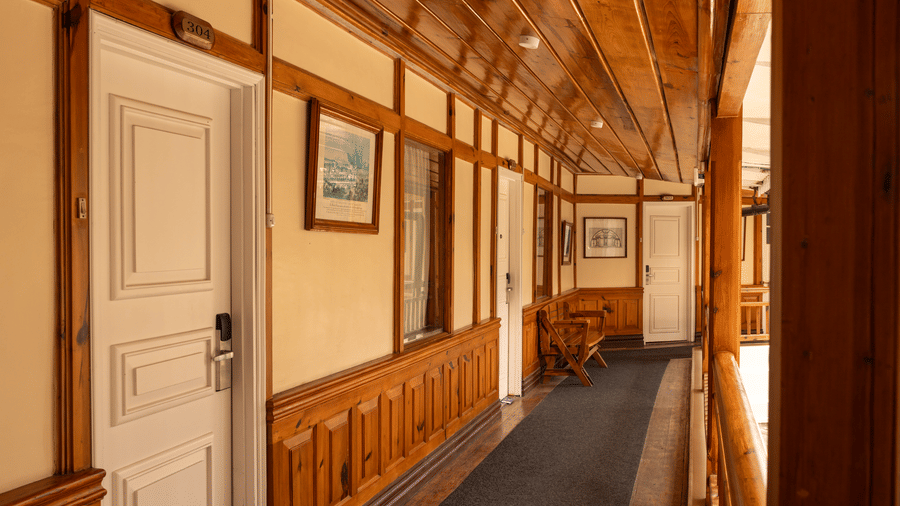 A corridor at The Heritage Club, Tripura, Castle, Shillong, showcasing several doors and wall arts.