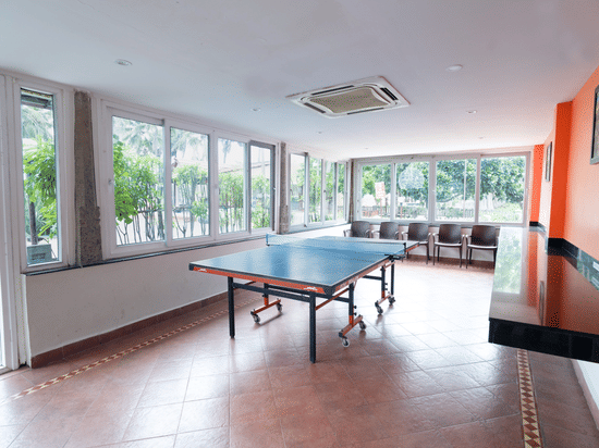 A table tennis board placed in a room with windows.