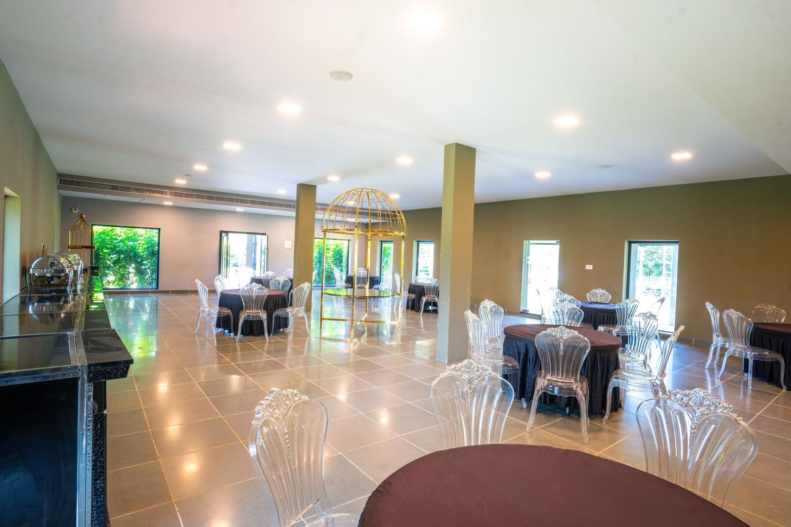 Interior of Love Letter at Darza Resort features round tables with dark tablecloths and clear chairs.