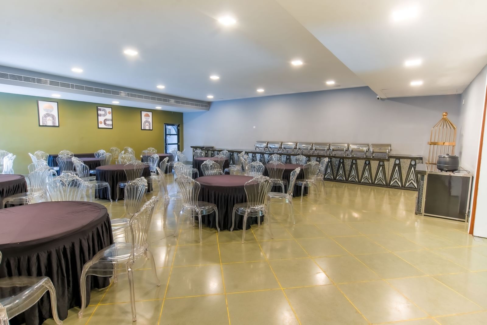 Interior of Royal Affair at Darza Resort features round tables with dark tablecloths and clear chairs, along with buffet serving stations.