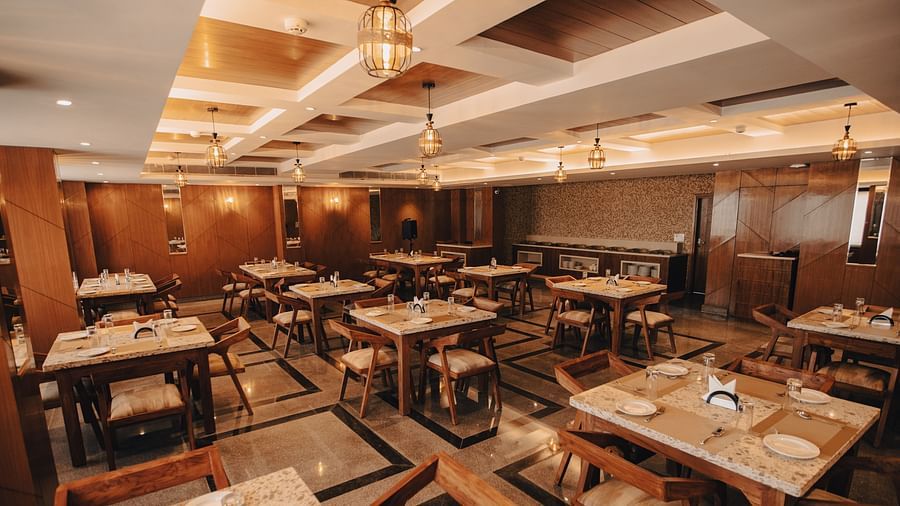 Clarks Inn Express Dehradun - interior view of the Bridge restaurant featuring numerous tables and chairs containing crockery