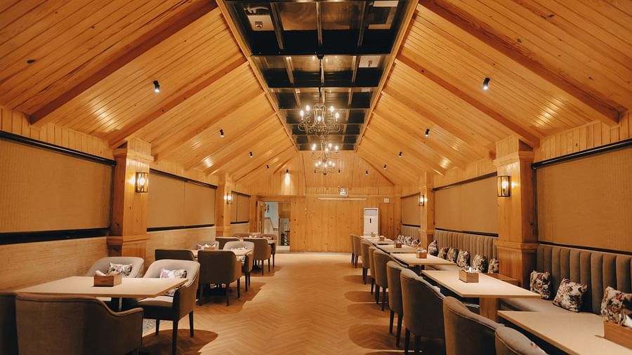 Clarks Inn Express Dehradun - interior view of the Clarks cafe featuring a wooden rood tables and an intricate chandelier