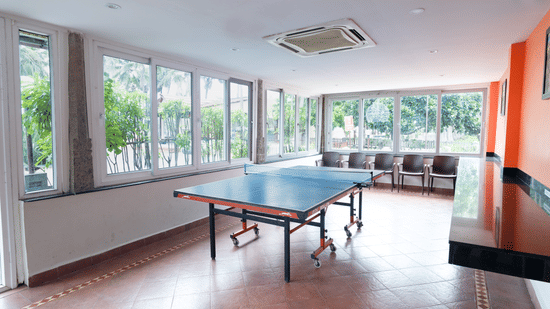 A table tennis board placed in a room with windows.