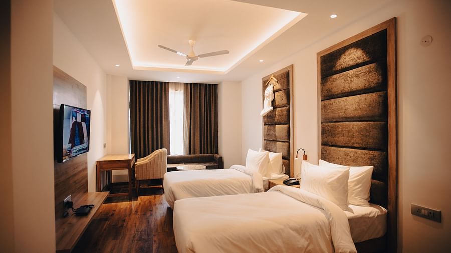 Clarks Inn Express Dehradun - interior view of the deluxe room featuring twin beds brown decor and yellow lighting