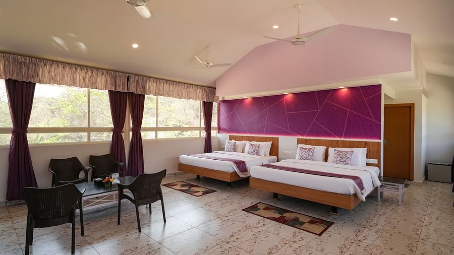 a bedroom with two king size beds and four chairs for sitting, with large windows on the side - MGM Whispering Wind's, Yelagiri