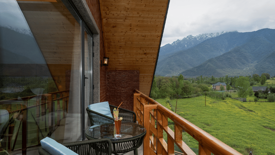 Private balcony at Mountnoor Sarovar Premiere, Pahalgam overlooking lush valleys and majestic Himalayan scenery.