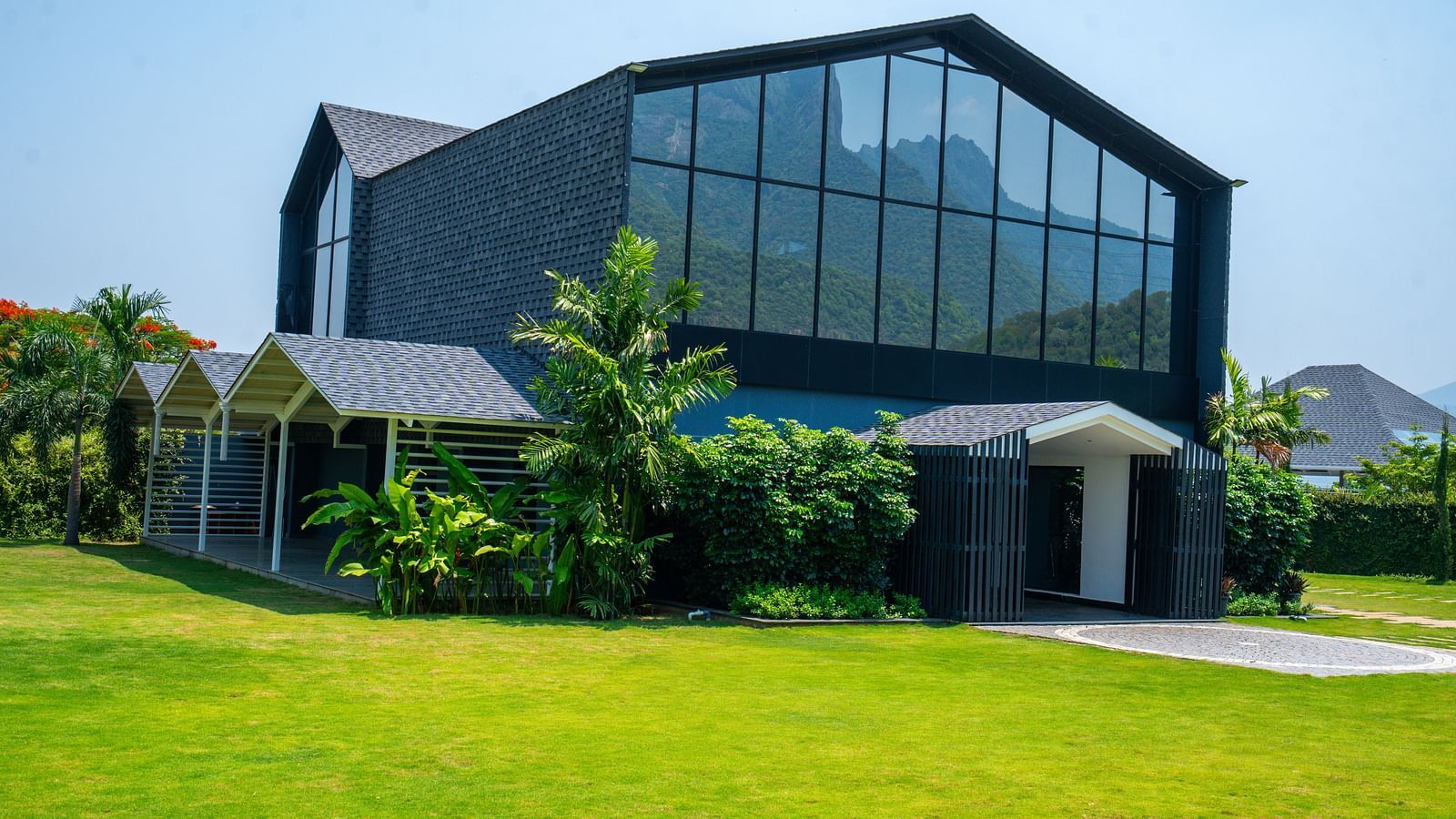 Love Letter at Darza Resort featuring a building with expansive glass windows and covered walkways is set on a lush green lawn under a clear sky.