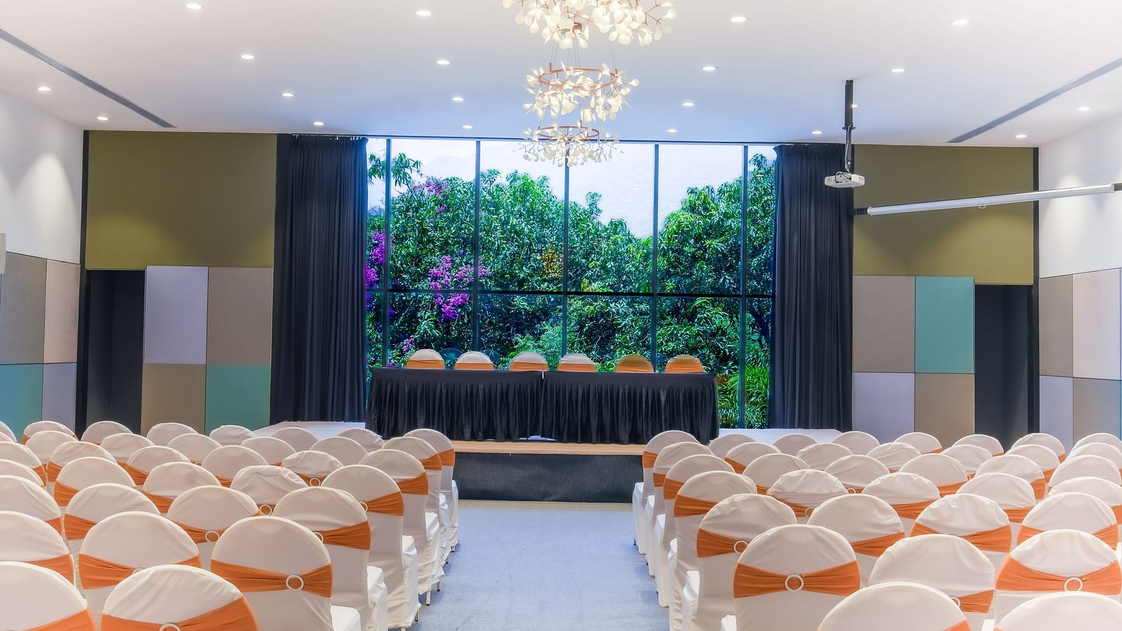 Royal Affair at Darza Resort is prepared with rows of white chairs decorated with orange sashes, facing a raised stage with a table.