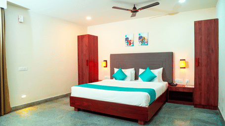 A bedroom with a bed, 2 pillows, and side tables at DNC Shevaroys Resorts and Spa.