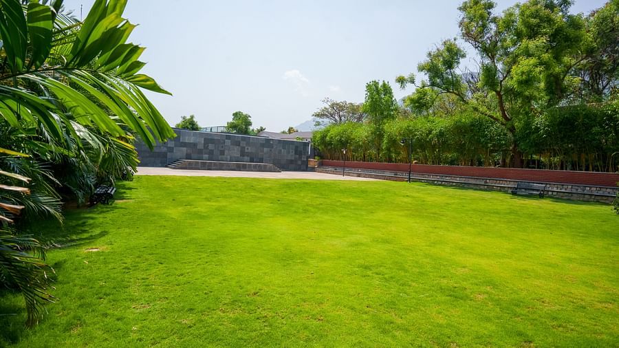 Enchante at Darza Resort featuring vibrant green lawn stretcheed out under a bright sky, bordered by lush trees, hedges, and a stone wall in the distance.