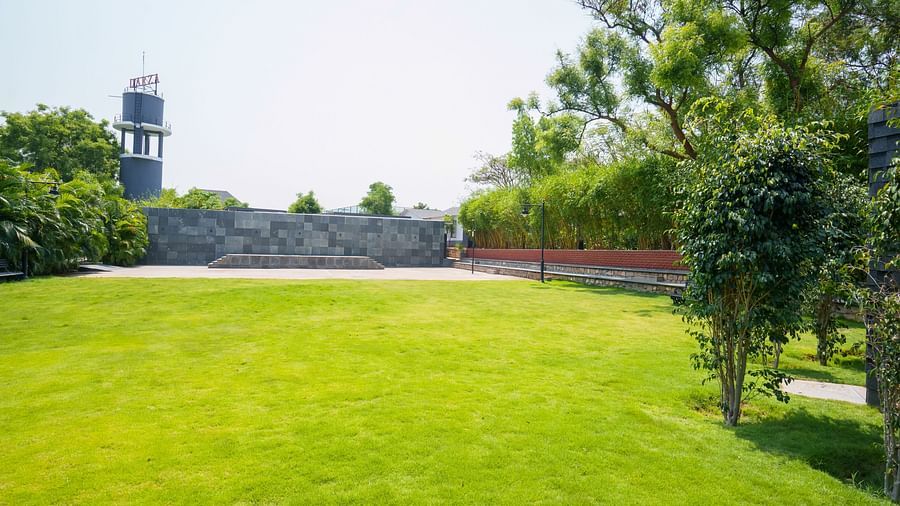 Enchante at Darza Resort featuring a wide expanse of bright green lawn is surrounded by trees, hedges, and a stone wall, with a tower visible in the distance under a clear sky.