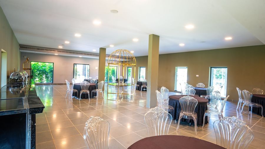 Interior of Love Letter at Darza Resort features round tables with dark tablecloths and clear chairs.