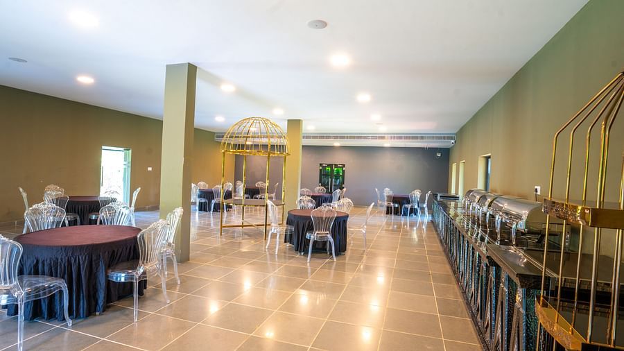 Interior of Love Letter at Darza Resort featuring a large, brightly lit room set up for dining with round tables, clear chairs, and buffet stations along one side.