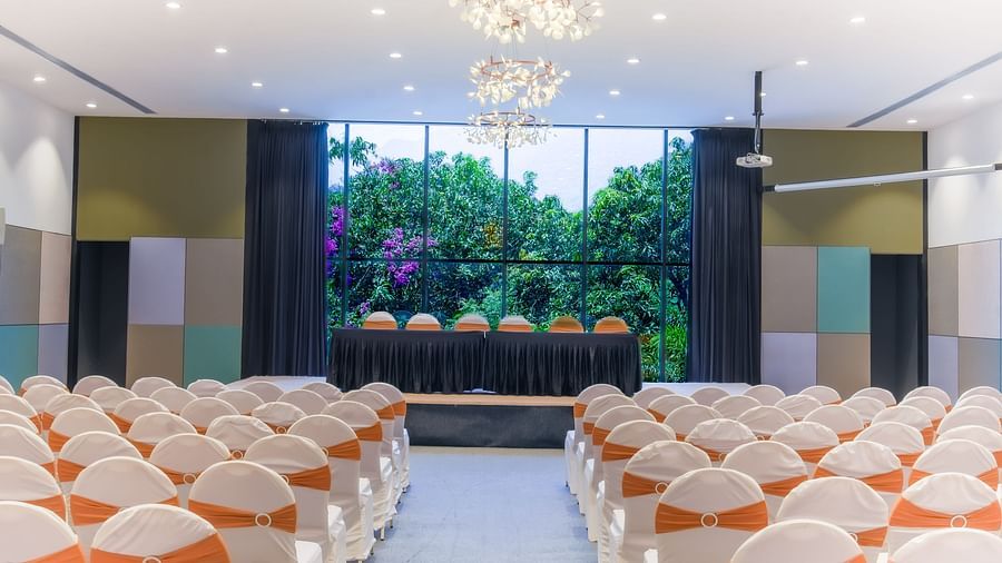 Royal Affair at Darza Resort is prepared with rows of white chairs decorated with orange sashes, facing a raised stage with a table.
