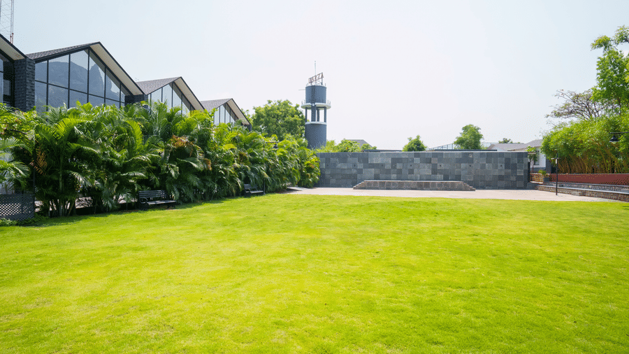 Enchante at Darza Resort featuring a lawn extended towards modern buildings and a tower under a bright, clear sky