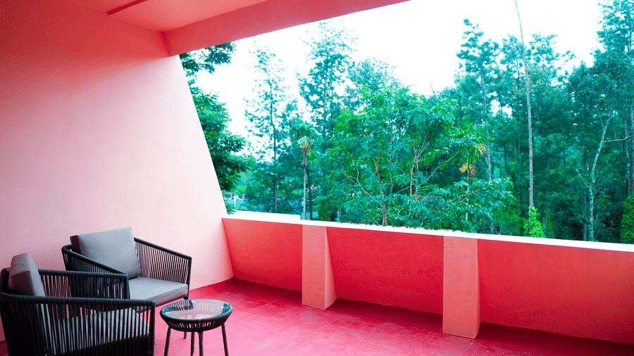 A balcony with chairs, a table, and a view of trees at DNC Shevaroys Resorts and Spa.