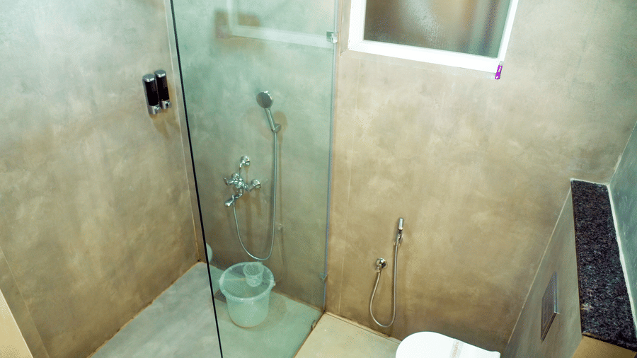 A bathroom with a shower area, a toilet, and a sink at DNC Shevaroys Resorts and Spa.