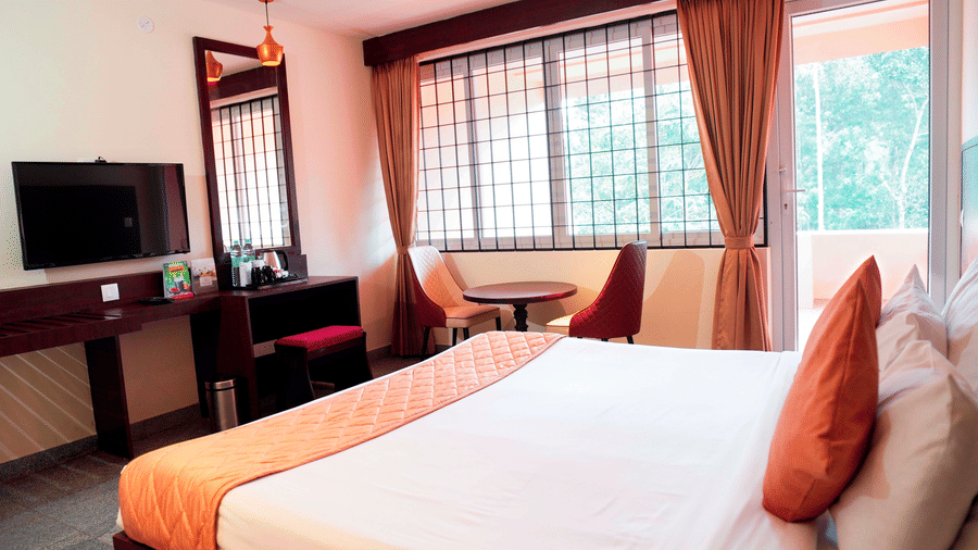 A bedroom with a bed, a television, and a desk at DNC Shevaroys Resorts and Spa.