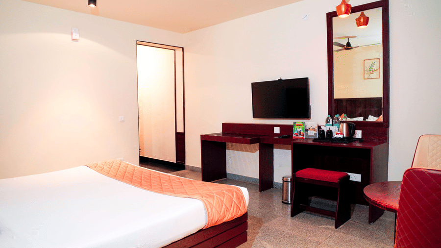 A bedroom with a bed, a desk, and a chair at DNC Shevaroys Resorts and Spa.