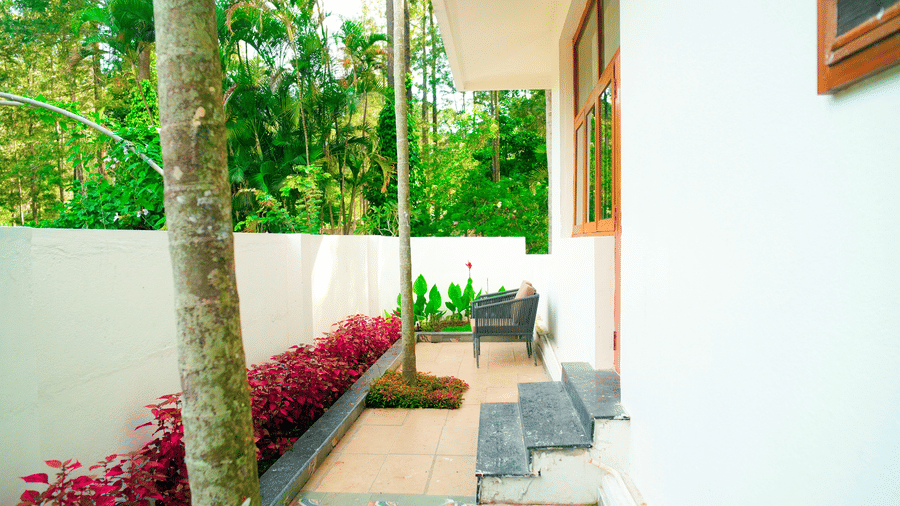 A walkway with plants and trees beside a building at DNC Shevaroys Resorts and Spa.